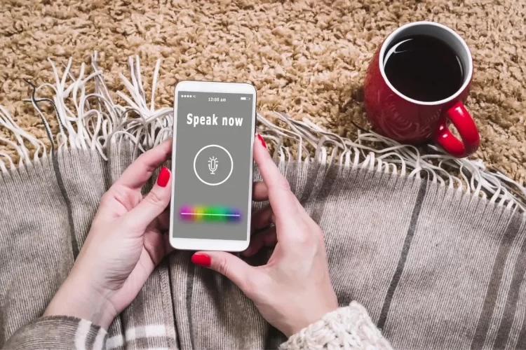 A woman performing Accessibility Testing on a smart phone with the text "speak now" visible.