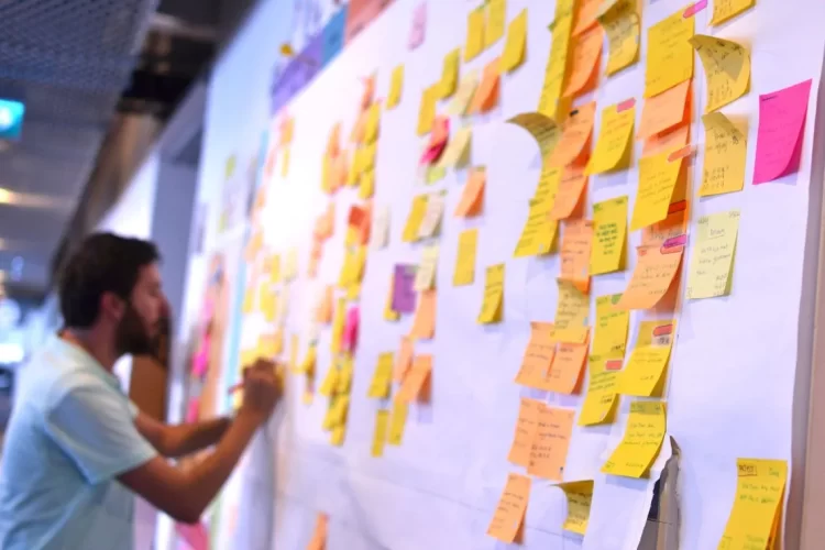 A man standing next to a wall covered in sticky notes.