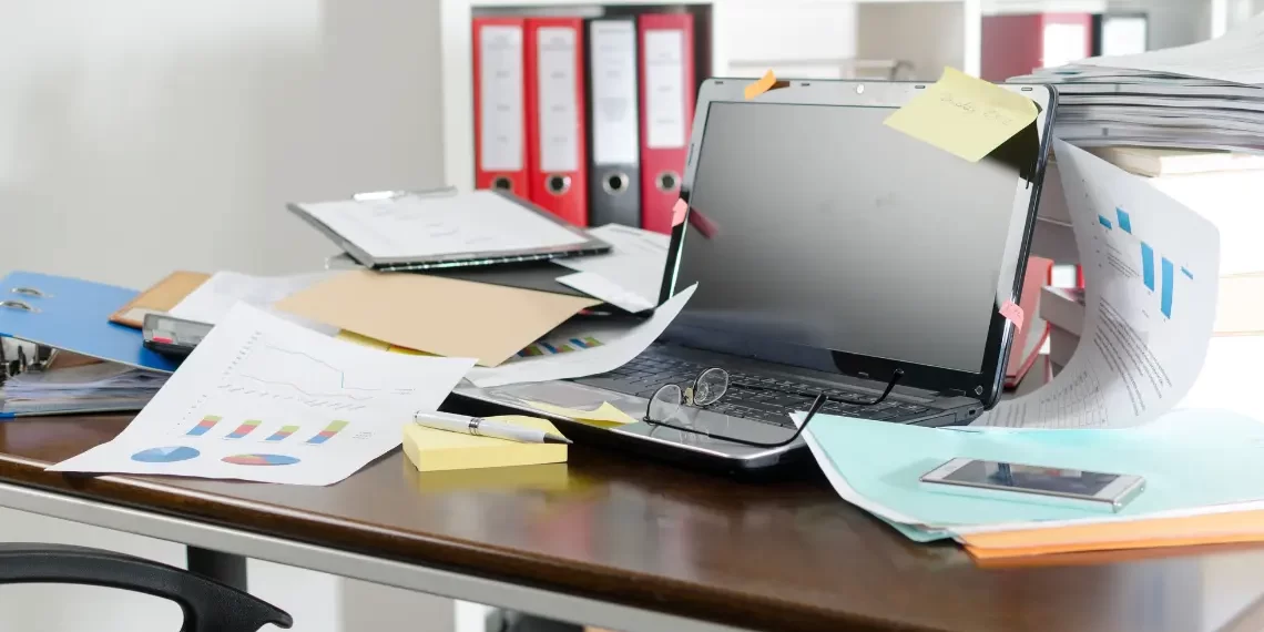 Before home office organization - cluttered desk with papers and laptop