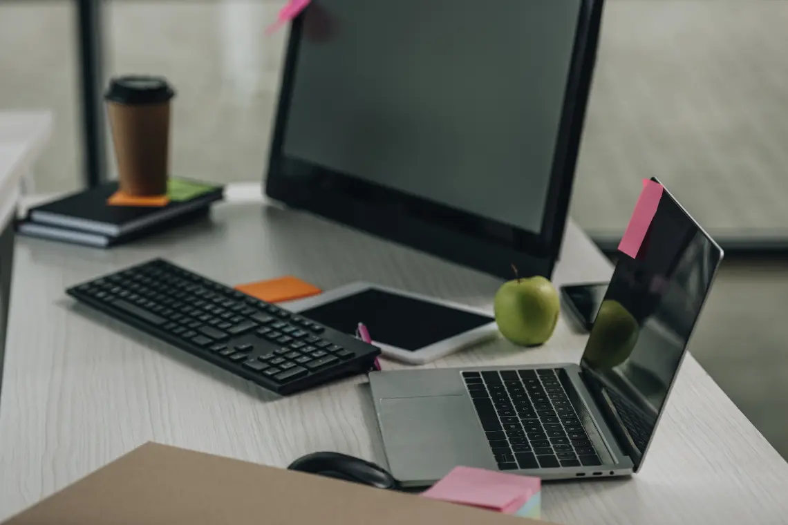Cluttered workspace with laptop, keyboard, and sticky notes