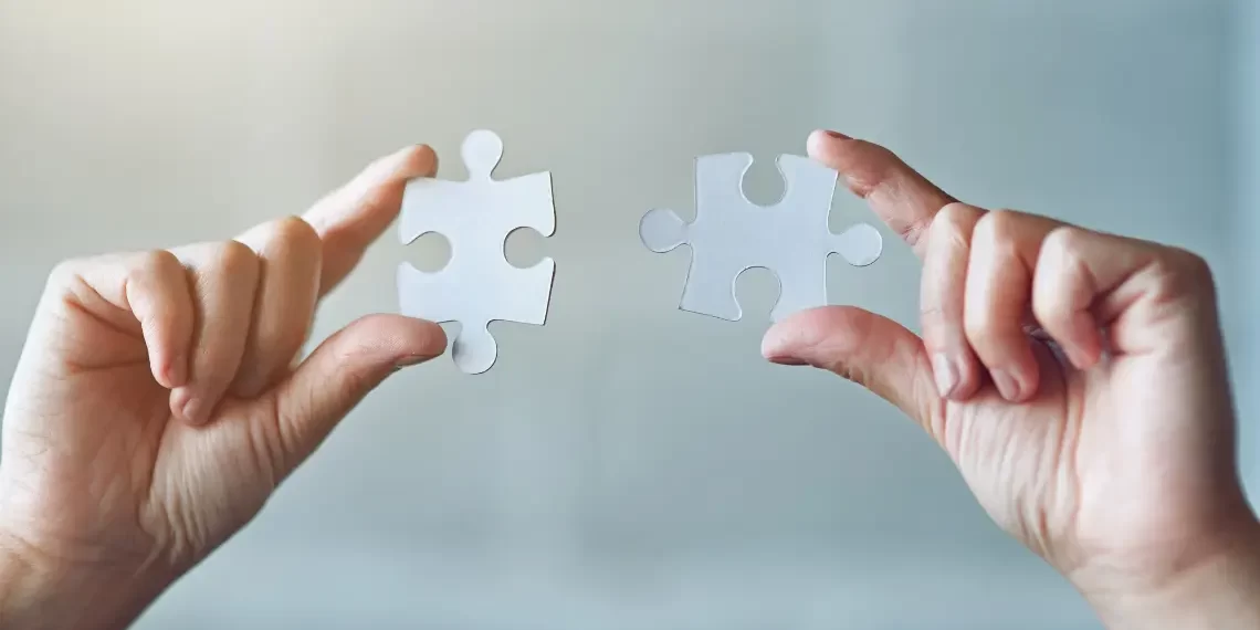 Hands connecting puzzle pieces, representing assembling skills on the Programming Roadmap.