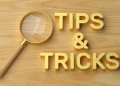 Magnifying glass focusing on the words Tips & Tricks on a wooden background