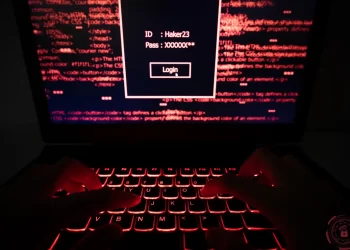 Anonymous user entering credentials on a secure login page with code in the background