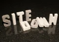 Concrete block letters spelling 'SITE DOWN' representing website downtime.
